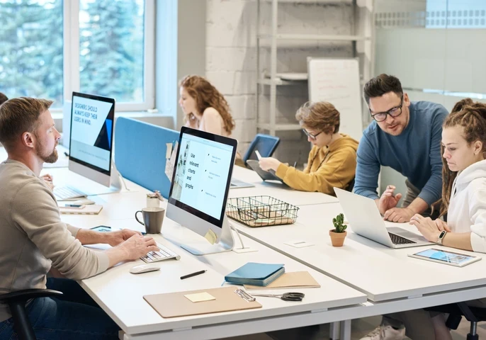 Employees sat at a large desk working on computers in a modern office