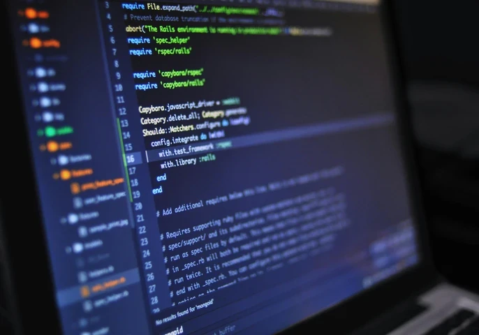 Code on a laptop screen in a dark room.