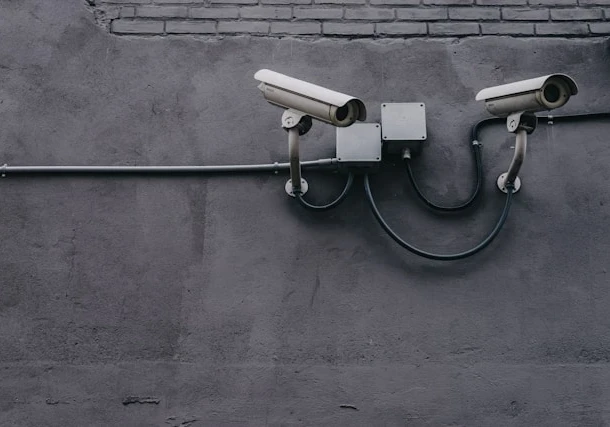 Two surveillance cameras mounted to a gray wall.