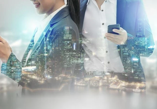 A cityscape of lit up skyscrapers projected onto female and male professionals