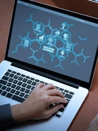 Someone working on a laptop with a mindmap with "machine learning" in the middle of the screen
