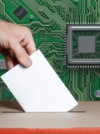 A hand placing a paper into a ballot box against a circuit board background.