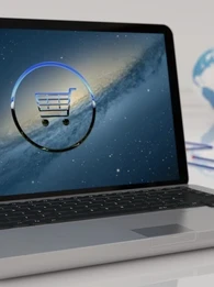 Laptop open on a laptop with a virtual representation of a shopping cart against a starry sky on the screen.