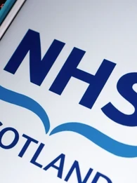NHS Scotland logo on a smartphone with a coding background.