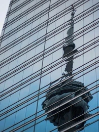 A tower's warped reflection in the window's of a skyscraper showing corruption and scandal underneath a perfect veneer.