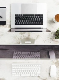 macbook and iMac computer on a desk with apple mouse and keyboard, and apple magic trackpad