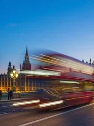 Image of London's Big Ben with a London red bus zooming past
