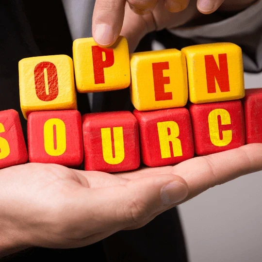 The words "Open Source" on red and yellow blocks held by a person in a suit.