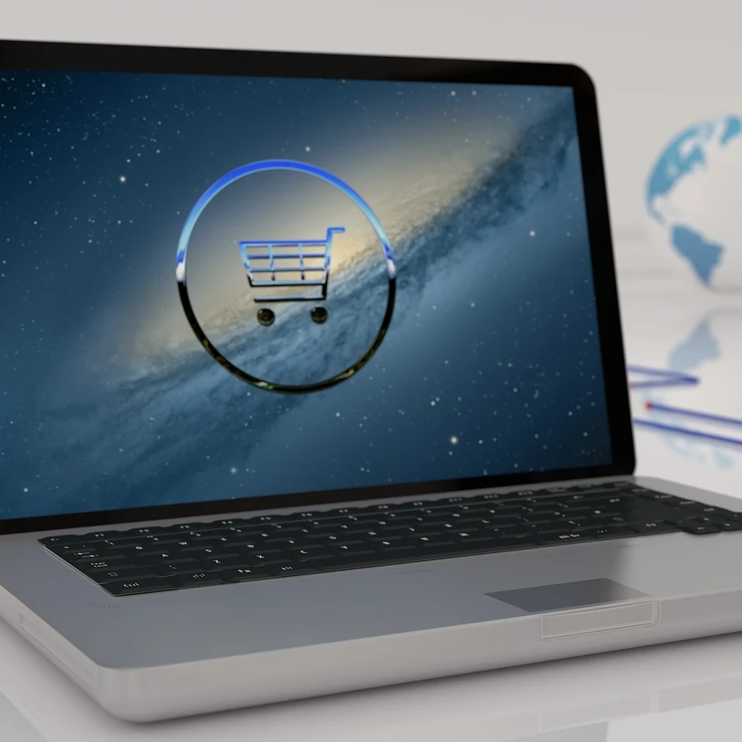 Laptop open on a laptop with a virtual representation of a shopping cart against a starry sky on the screen.