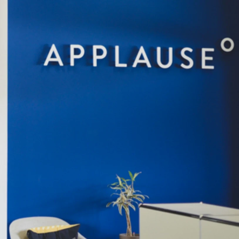 Applause logo on a dark blue wall in an office