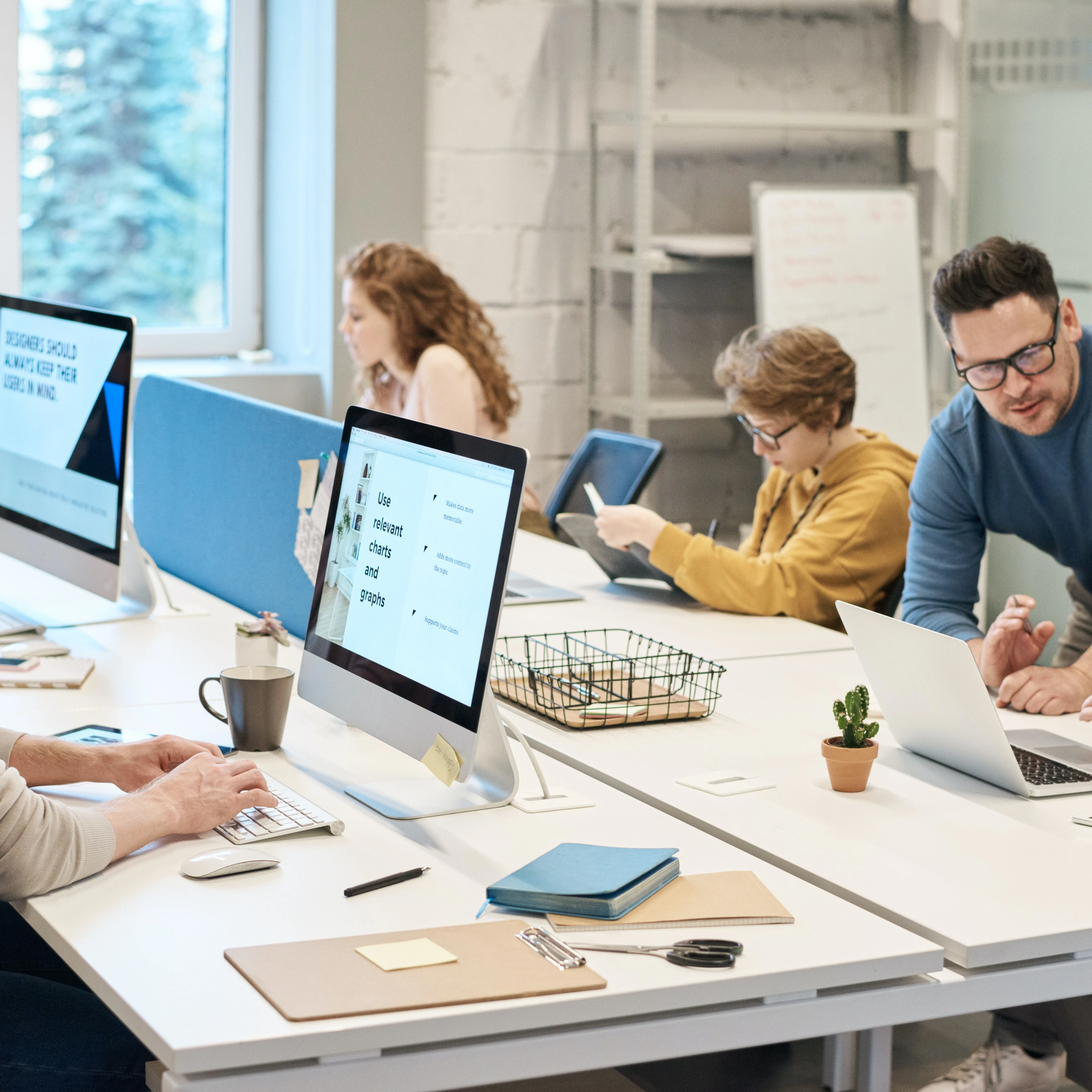 Employees sat at a large desk working on computers in a modern office