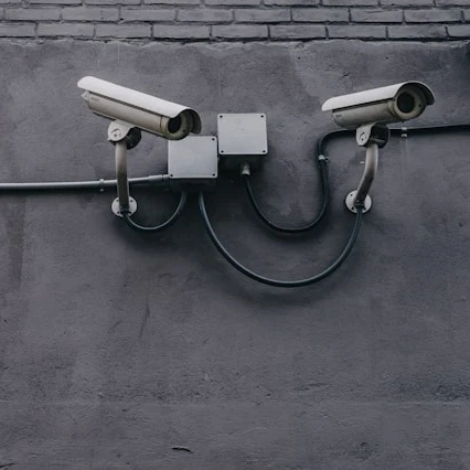 Two surveillance cameras mounted to a gray wall.