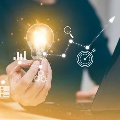 A person holding up a lightbulb while sitting in front of a laptop with icons floating around.