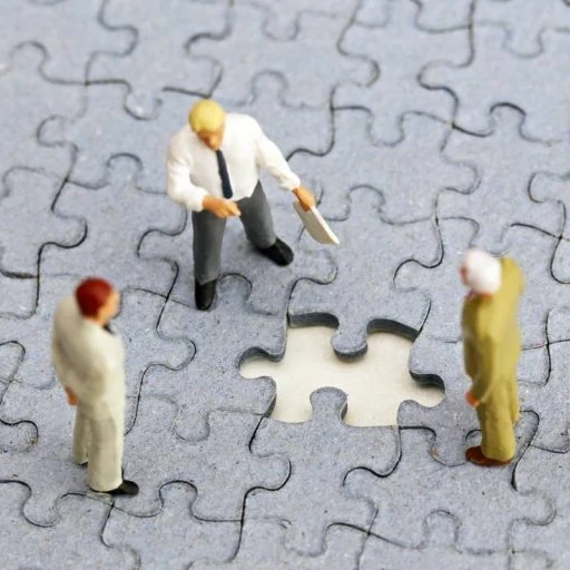 Three figurines surrounding a missing puzzle piece.