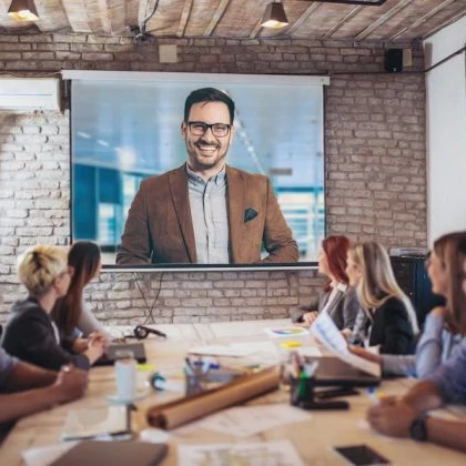 People sitting at a desk looking up at at video conferencing screen.