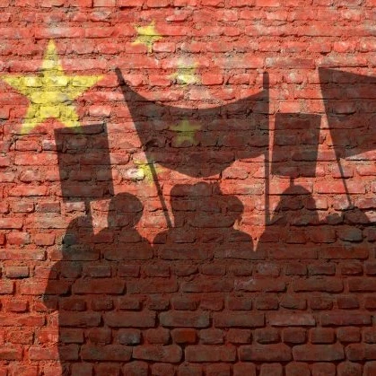A shadow of a protesting crowd with banners against a brick wall with the EU logo on it in yellow