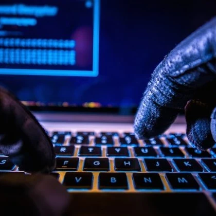 Gloved hands typing on a laptop to show a hacker working